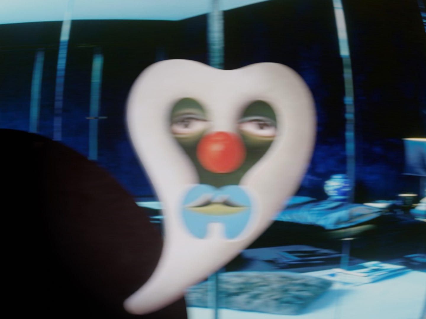 A seemingly intimate photograph of a sad character in clown makeup, in a lush modern interior