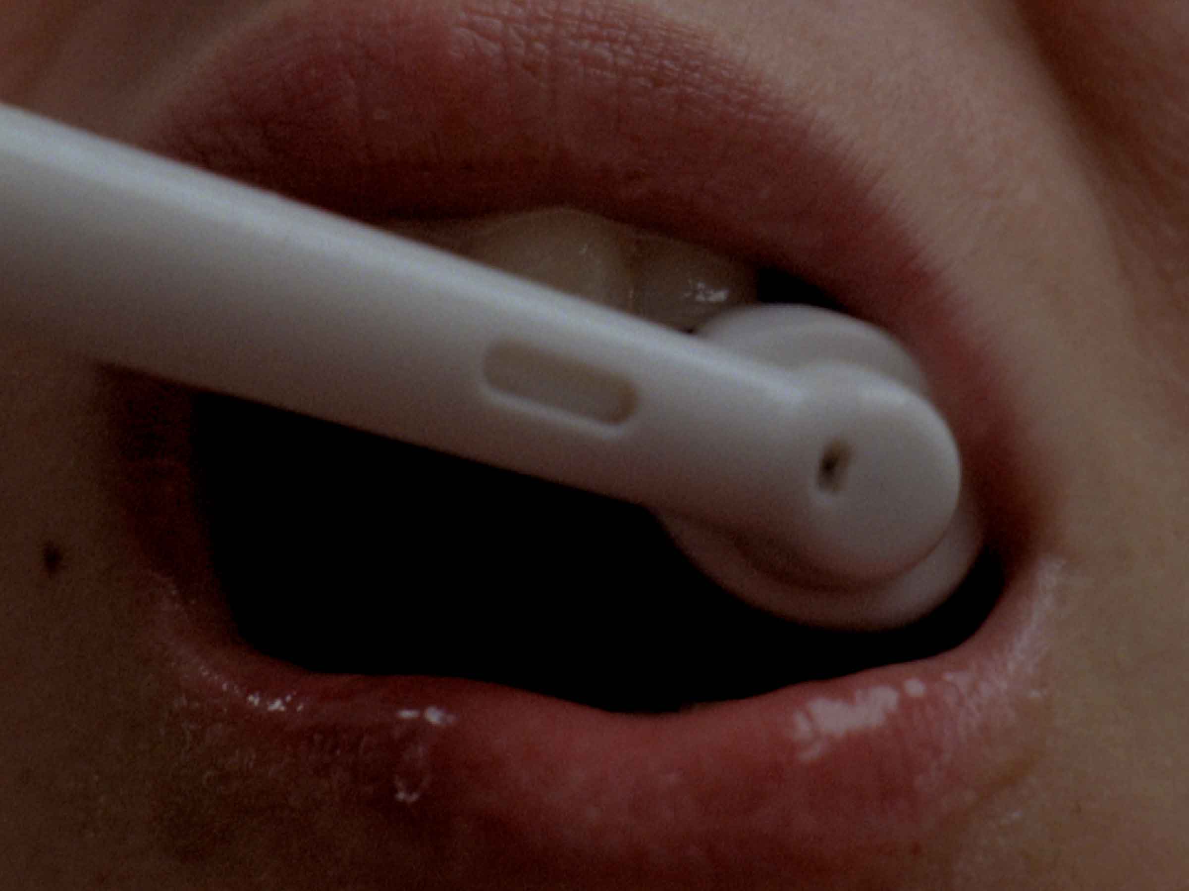16mm film still: a woman brushing her teeth