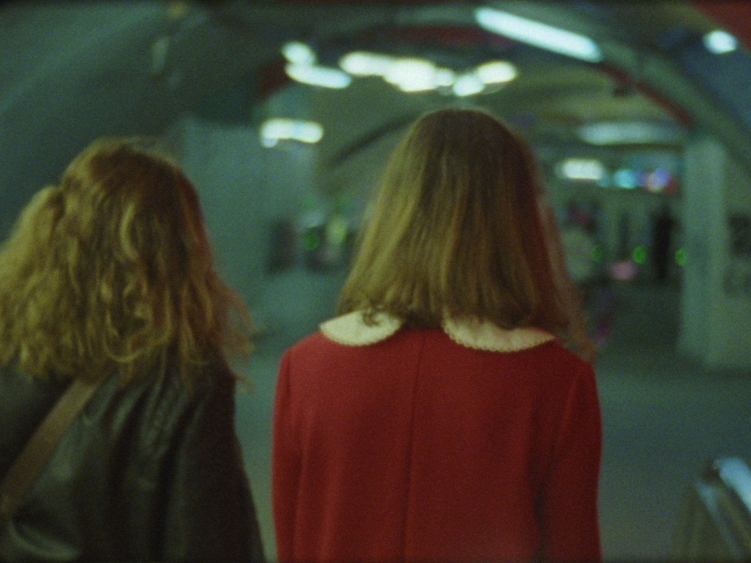 16mm film still: a woman in a red dress walking in a station of the rapid transit system in Paris
